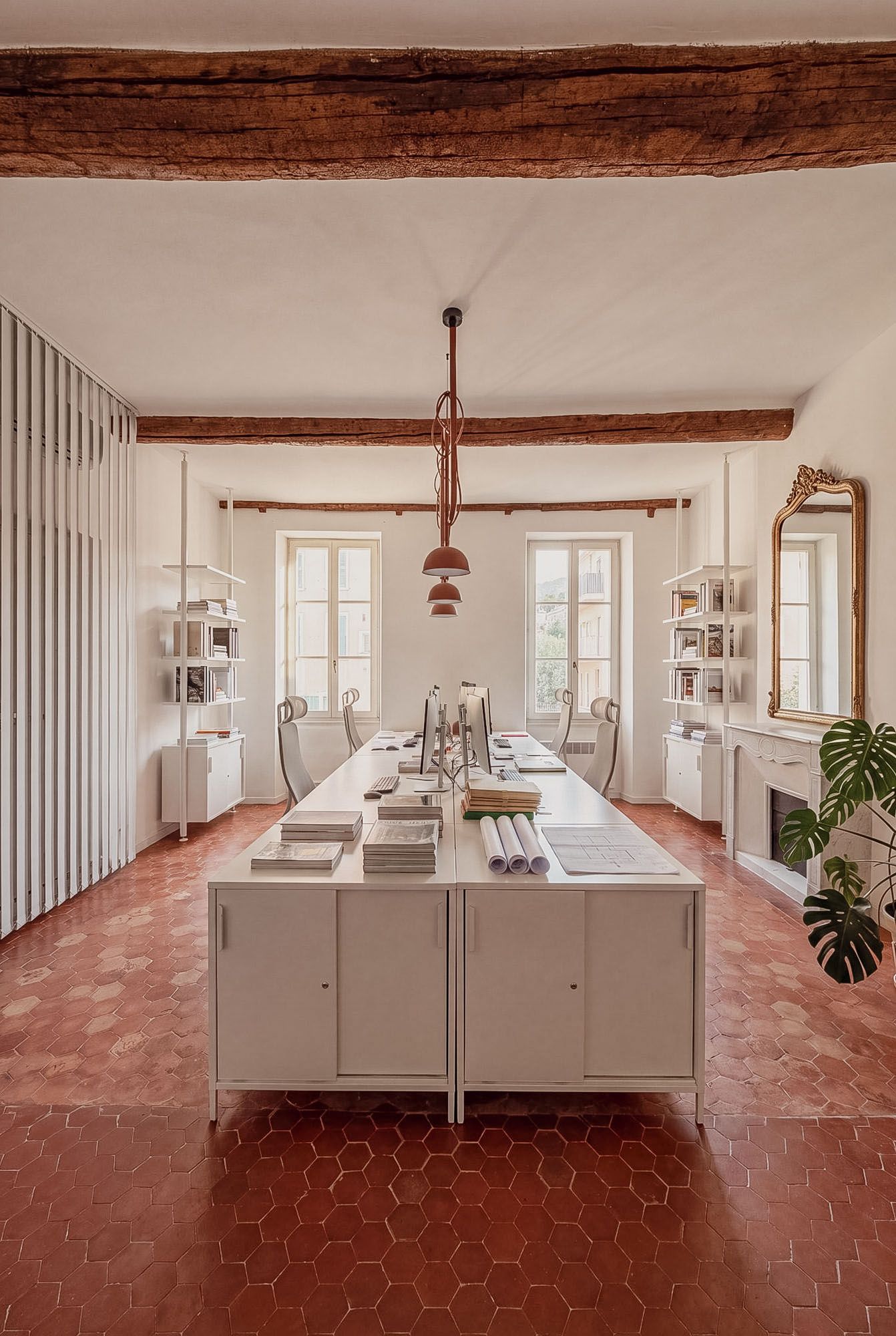 Sarkisian Touzet Architecture studio in Villefranche-sur-Mer: large shared work table, exposed wooden beams, Provençal terracotta floor.