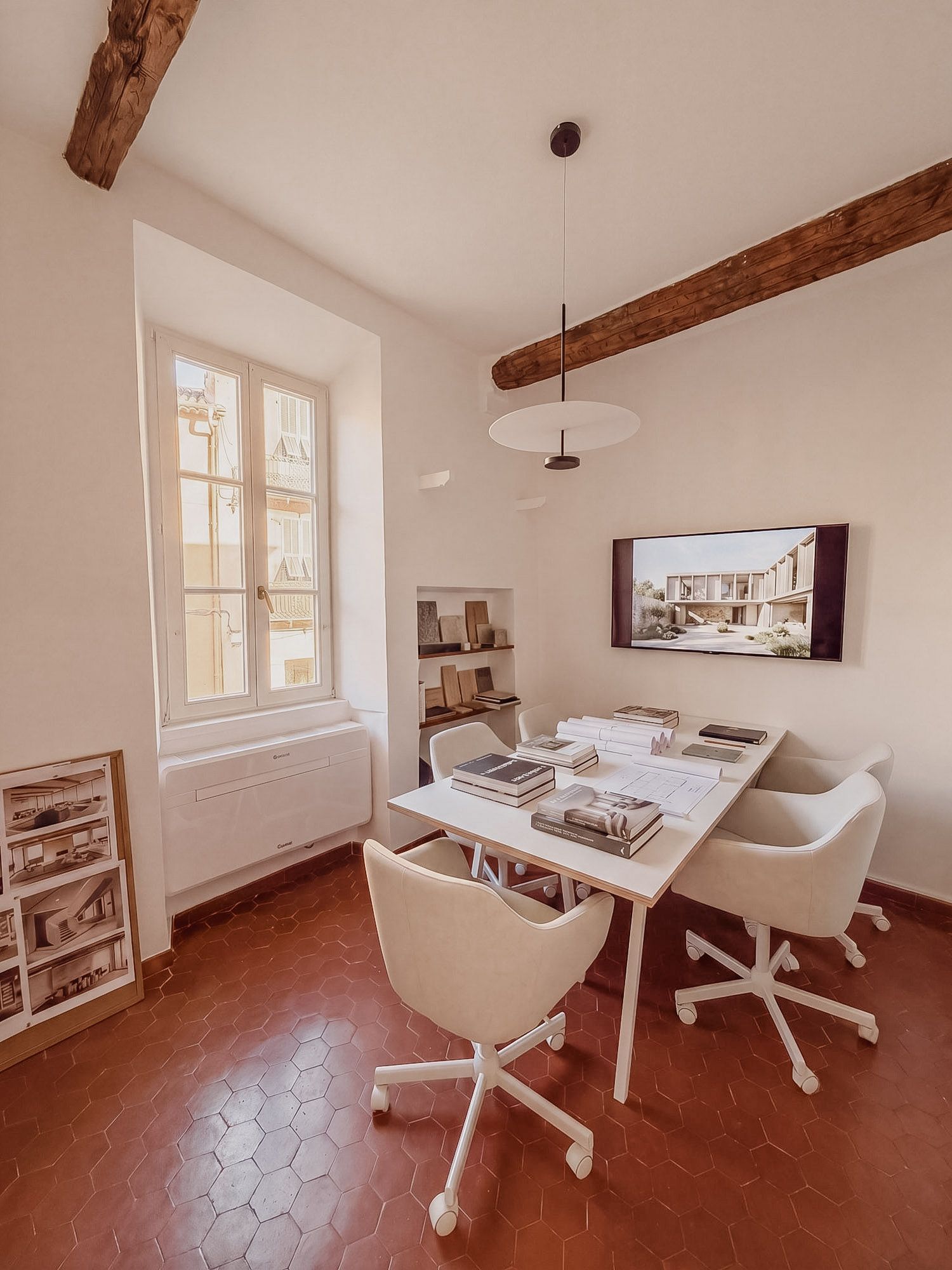 Meeting room of Sarkisian Touzet architecture studio in Villefranche-sur-Mer: project table, material samples and presentation screen, exposed beams.